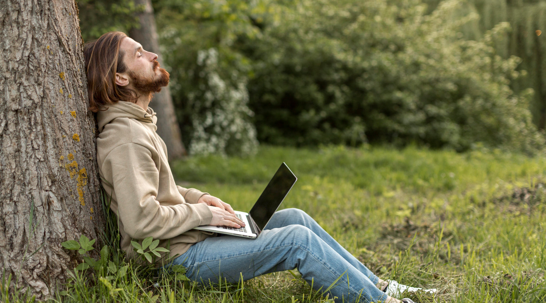 Man sitting in forest with a high quality refurbished laptop for cheap..